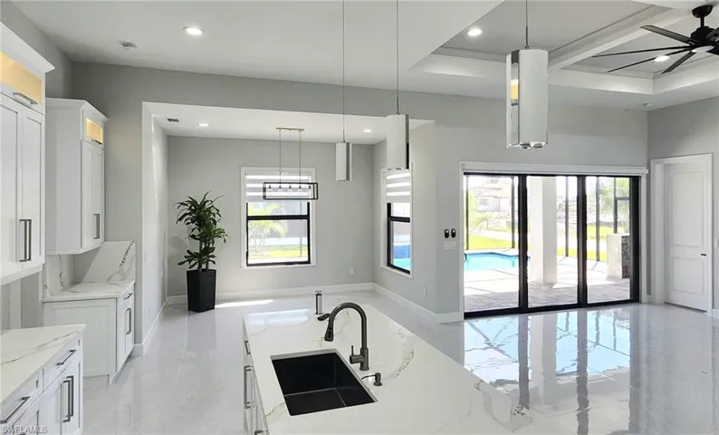 Kitchen with pendant lighting, white cabinets, ceiling fan, and sink