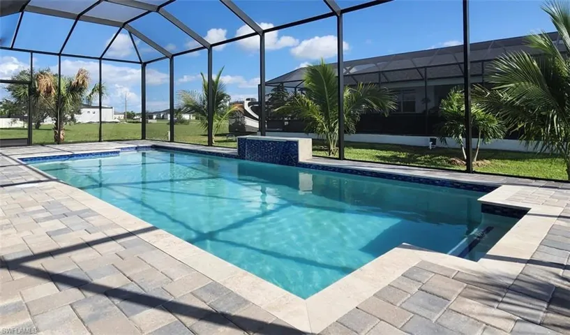 View of swimming pool featuring glass enclosure, a patio area, and a yard