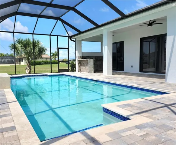 View of pool with a lanai, ceiling fan, a patio area, and a yard