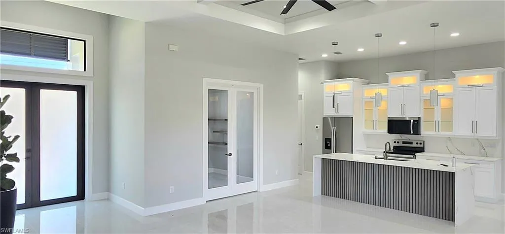 Kitchen featuring french doors, a kitchen island with sink, appliances with stainless steel finishes, and ceiling fan