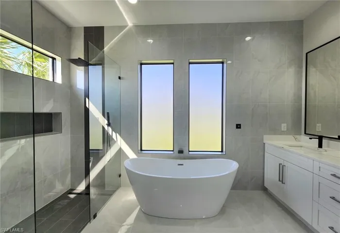Bathroom with tile walls, tile patterned flooring, vanity, and plus walk in shower