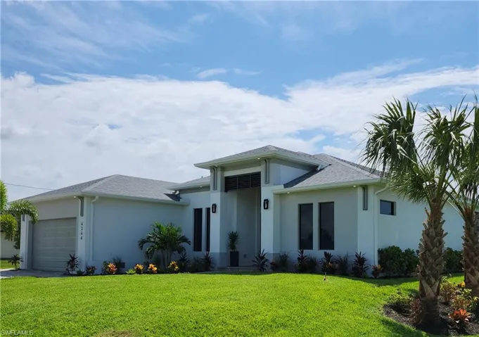 View of front of house with a garage and a front lawn