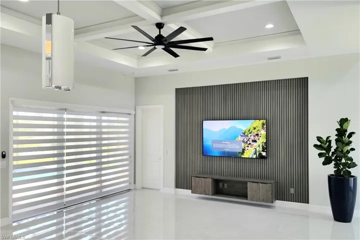 Living room featuring beam ceiling, tile patterned flooring, ceiling fan, and coffered ceiling