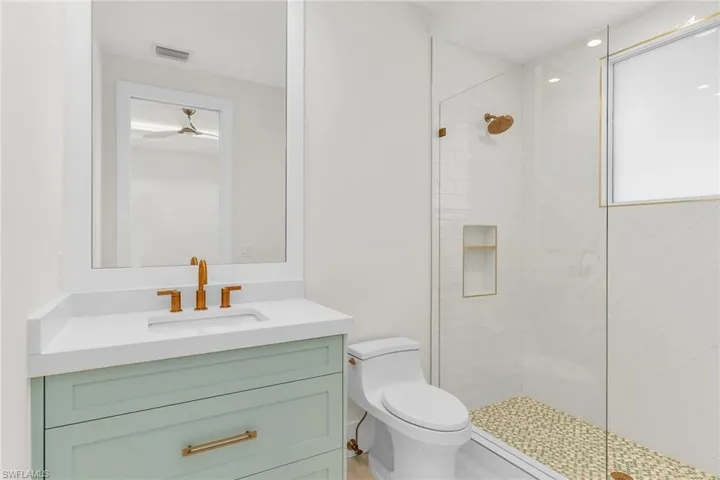 Bathroom with toilet, a stall shower, vanity, and visible vents