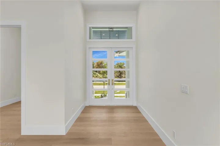 Entryway featuring french doors, baseboards, and light wood-style floors