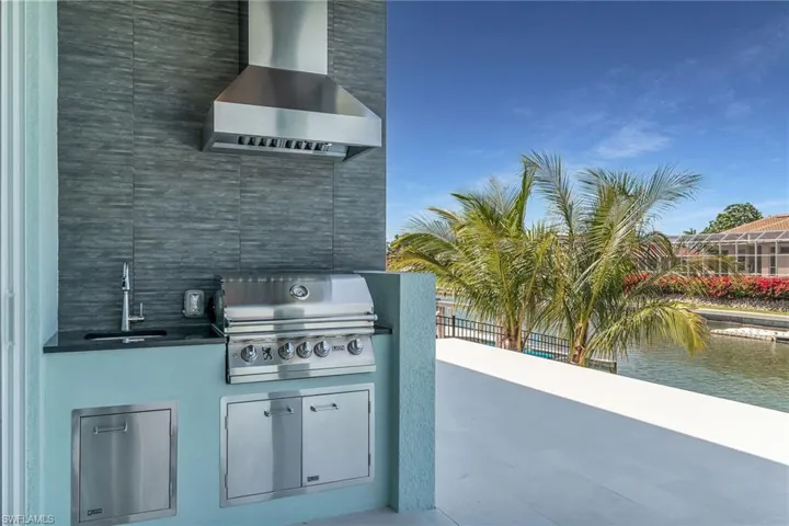 View of patio / terrace with area for grilling, a sink, and a water view