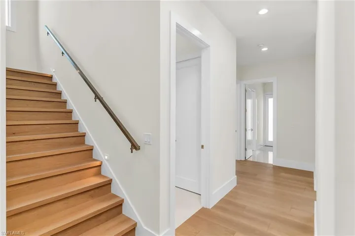 Stairs with wood finished floors, baseboards, and recessed lighting