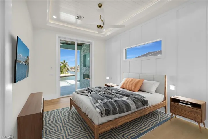 Virtually Staged - Primary Bedroom featuring visible vents, access to exterior, a tray ceiling, and light wood-style floors
