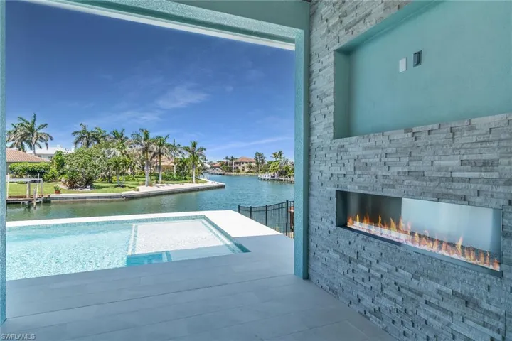 View of swimming pool featuring an outdoor stone fireplace and a water view