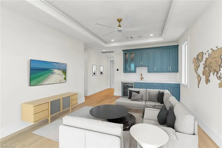 Virtually Staged - Living area with a tray ceiling, beverage cooler, light wood-style floors, and indoor wet bar