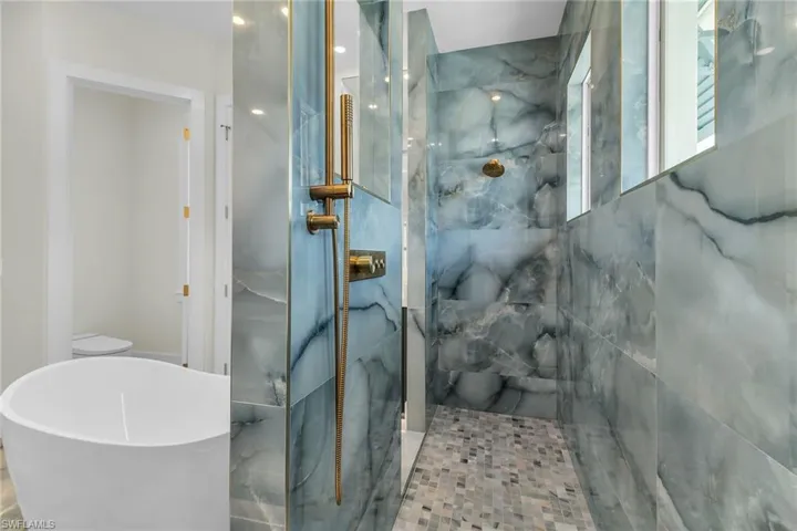 Full bath featuring a freestanding bath and a marble finish shower