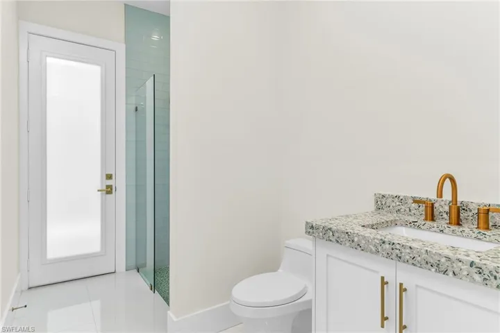 Full bath featuring a tile shower, toilet, tile patterned flooring, and baseboards