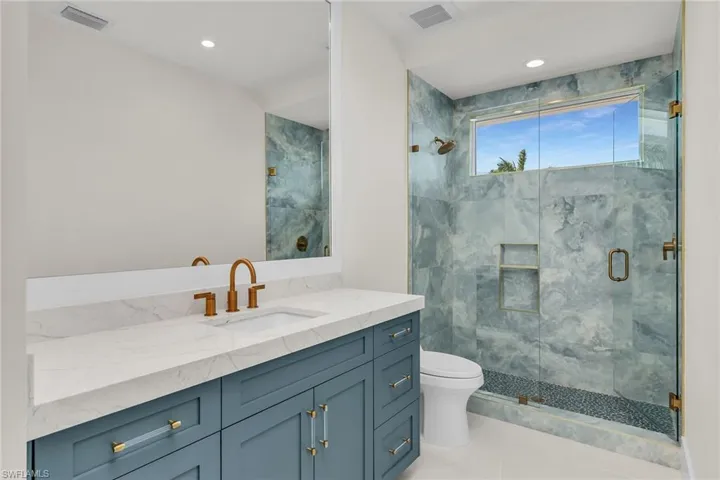 Full bathroom with a shower stall, vanity, visible vents, and toilet