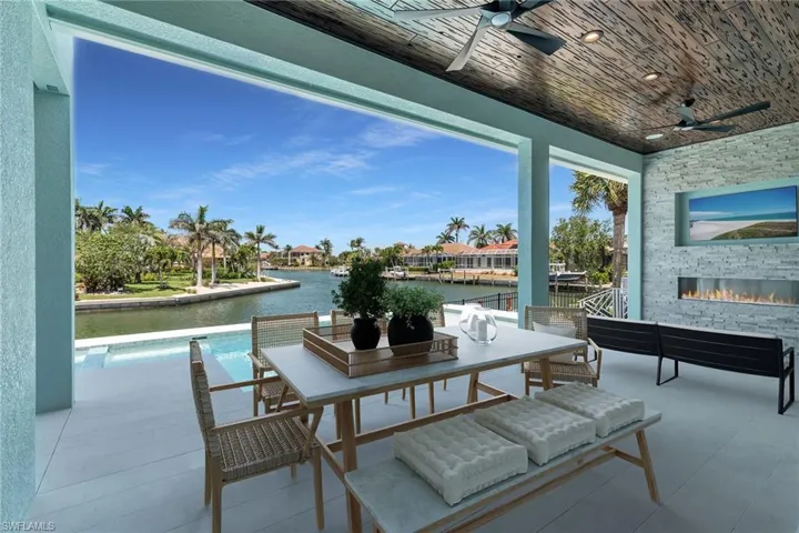 Virtually Staged - View of patio featuring a ceiling fan, outdoor dining area, and an outdoor stone fireplace
