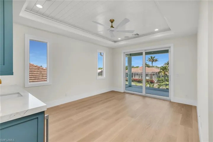 Unfurnished living room with light wood finished floors, ceiling fan, baseboards, and a raised ceiling