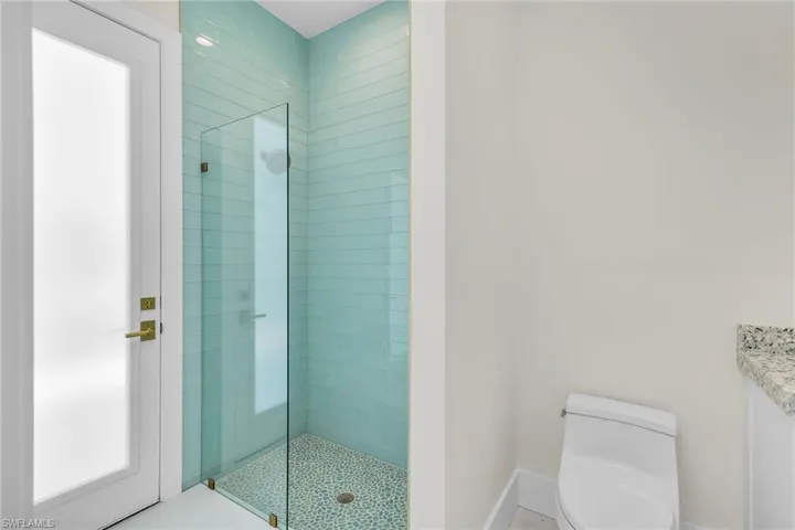 Bathroom with a shower stall, baseboards, and toilet