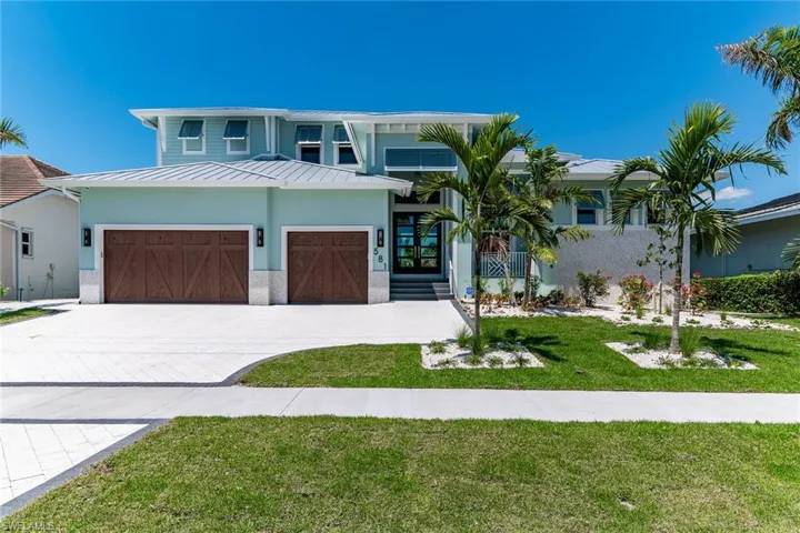 View of front of house featuring a standing seam roof, stucco siding, decorative driveway, metal roof, and a front lawn