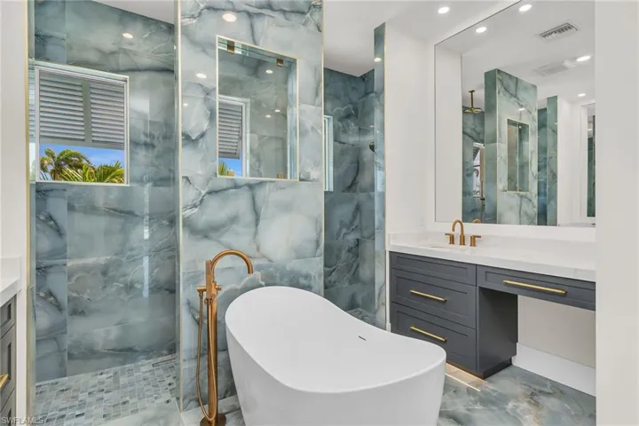 Bathroom with a soaking tub, vanity, visible vents, marble finish floor, and a marble finish shower