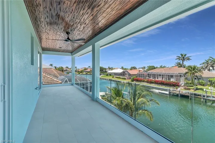 Balcony with a water view, ceiling fan, and a residential view