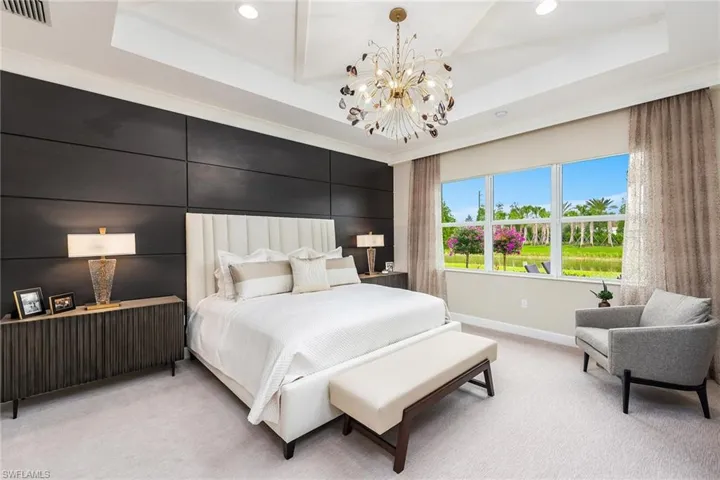 Carpeted bedroom featuring a chandelier and a tray ceiling