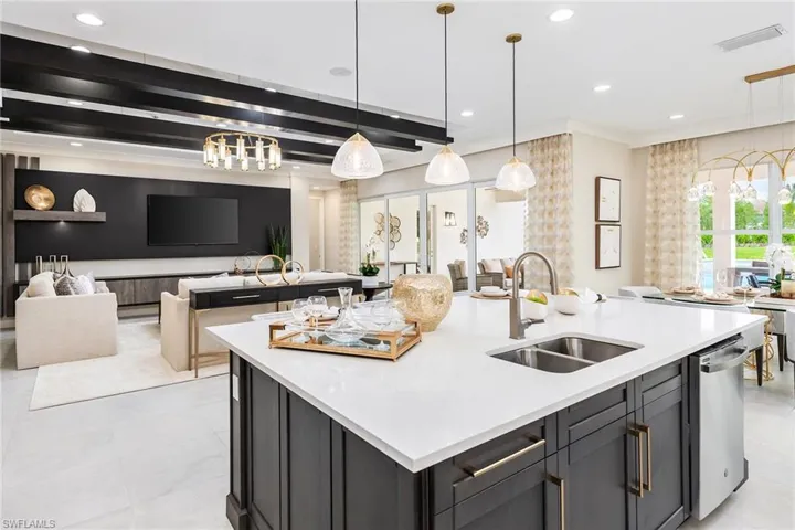 Kitchen featuring a kitchen island with sink, sink, pendant lighting, an inviting chandelier, and dishwasher
