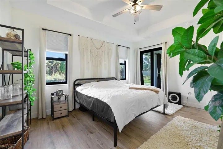 Bedroom featuring access to outside, hardwood / wood-style flooring, a raised ceiling, and ceiling fan