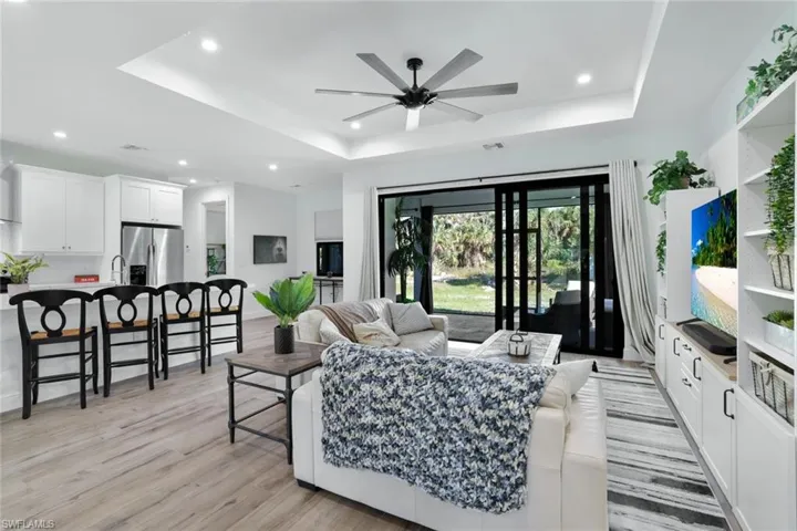 Living room with a tray ceiling, ceiling fan, light hardwood / wood-style flooring, and sink