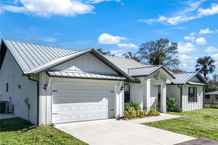Modern farmhouse style home with board and batten siding, a standing seam roof, an attached garage, and concrete driveway