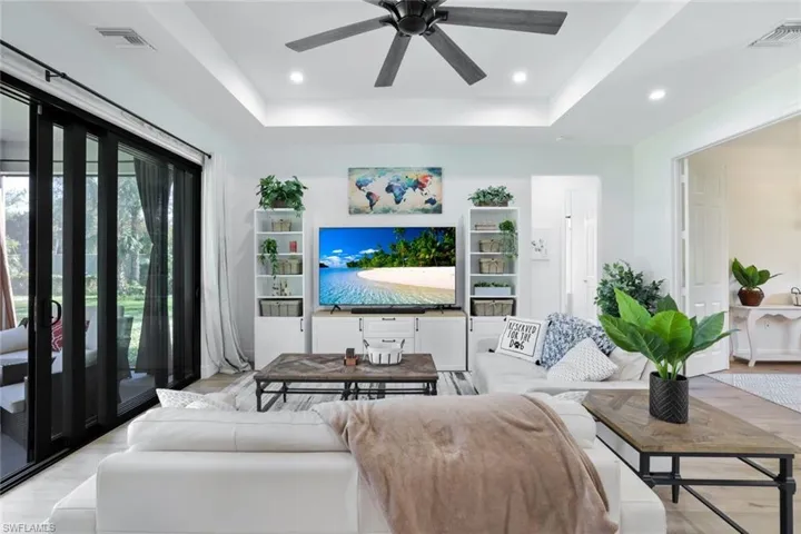 Living room featuring a tray ceiling, light hardwood / wood-style flooring, and ceiling fan
