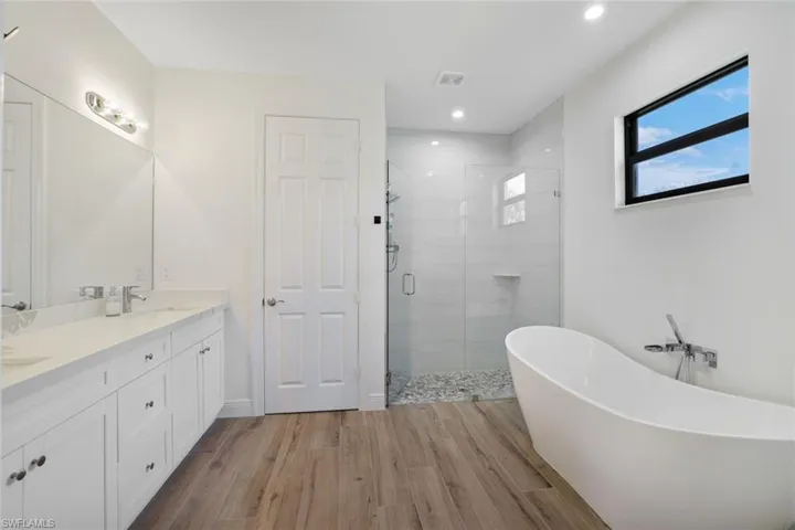 Bathroom featuring plus walk in shower, wood-type flooring, and vanity