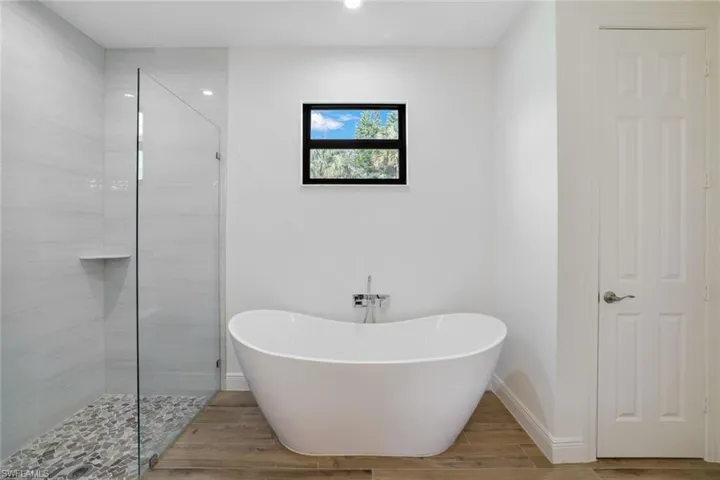 Bathroom with independent shower and bath and hardwood / wood-style flooring