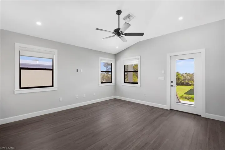 Unfurnished room featuring ceiling fan, dark wood-type flooring, and vaulted ceiling