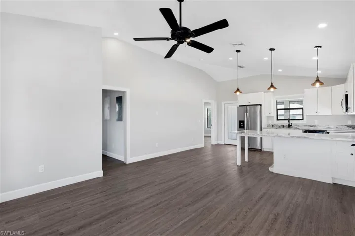 Kitchen with white cabinets, ceiling fan, decorative light fixtures, dark hardwood / wood-style flooring, and stainless steel fridge with ice dispenser