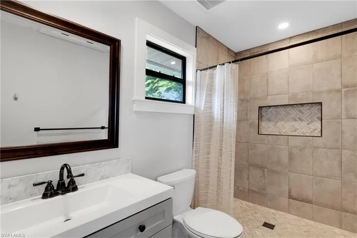 Bathroom featuring vanity, toilet, and curtained shower