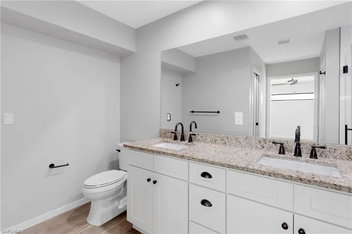 Bathroom with vanity, ceiling fan, toilet, and wood-type flooring