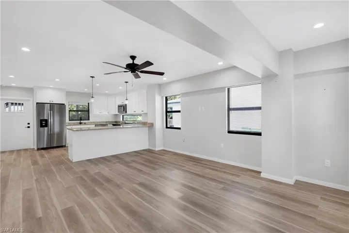 Kitchen with kitchen peninsula, stainless steel appliances, light hardwood / wood-style flooring, white cabinetry, and hanging light fixtures