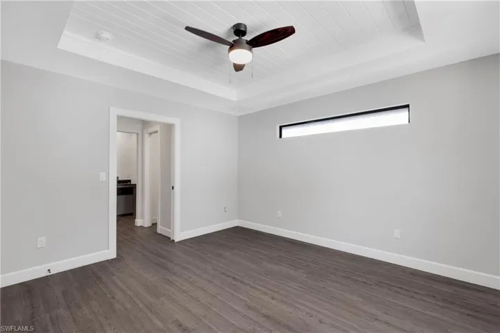 Unfurnished room with wooden ceiling, a raised ceiling, ceiling fan, and dark wood-type flooring