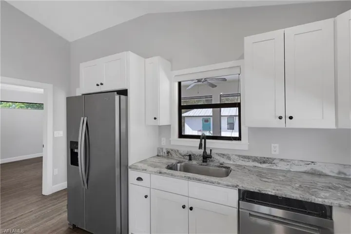 Kitchen featuring white cabinetry, sink, dark hardwood / wood-style flooring, vaulted ceiling, and appliances with stainless steel finishes