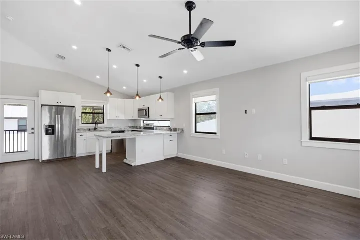 Kitchen with white cabinets, a wealth of natural light, appliances with stainless steel finishes, and vaulted ceiling