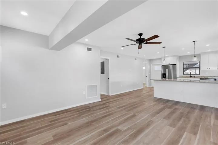 Unfurnished living room featuring ceiling fan, light hardwood / wood-style floors, and sink