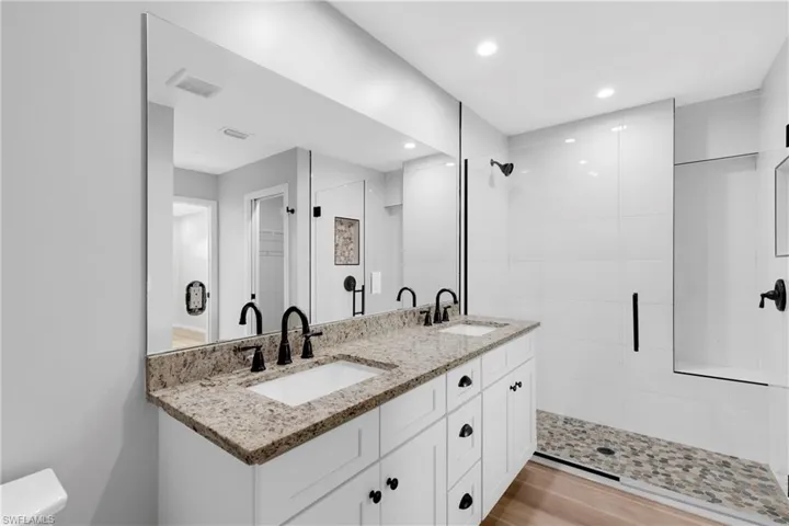Bathroom featuring tiled shower, vanity, and hardwood / wood-style flooring