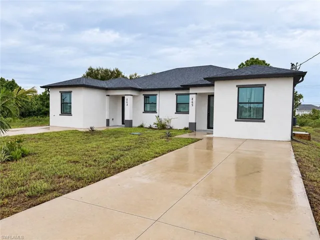 Contemporary exterior featuring white stucco siding, a multi-faceted roofline, dark-framed windows, and a concrete driveway