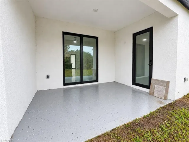 Covered patio featuring a concrete floor with a grey epoxy finish, stucco exterior walls, a sliding glass door, and a single-lite glass entry door