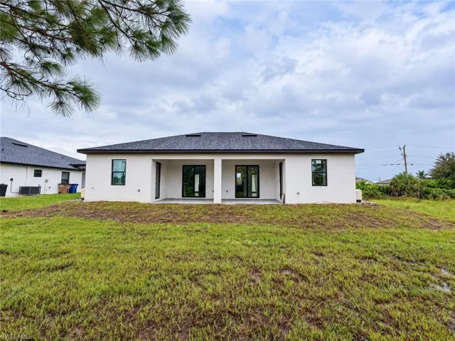 Stucco exterior with a hip roof, featuring a covered rear patio, double glass-panel entry doors, and large windows with dark trim