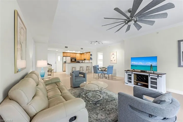 Living room featuring ornamental molding, rail lighting, and ceiling fan