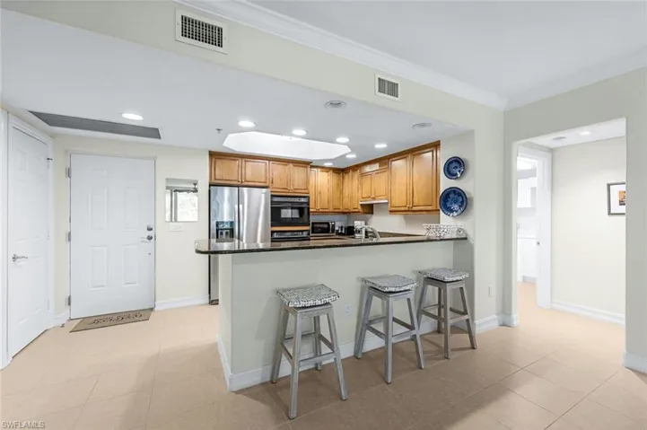 Kitchen featuring light tile patterned floors, a kitchen bar, kitchen peninsula, and stainless steel appliances