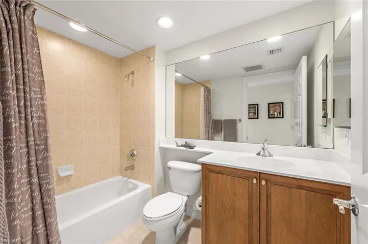 Full bathroom with tile patterned floors, toilet, shower / bath combination with curtain, and vanity