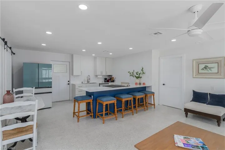 Kitchen with a breakfast bar, a peninsula, a barn door, white cabinets, and freestanding refrigerator