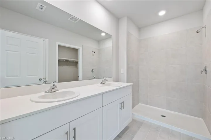 Bathroom featuring tile patterned floors, a tile shower, and vanity