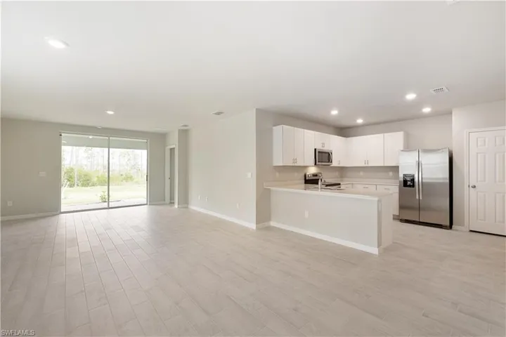 Kitchen with appliances with stainless steel finishes, white cabinetry, light wood-type flooring, and kitchen peninsula